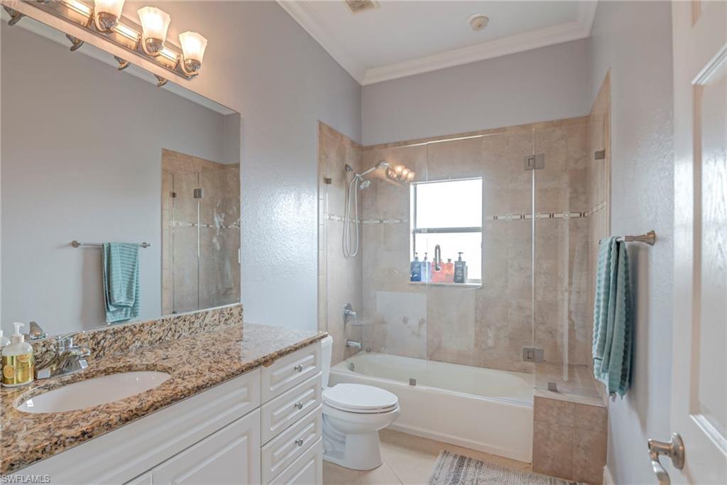 Bathroom with vanity, tiled shower / bath, crown molding, and light tile patterned flooring