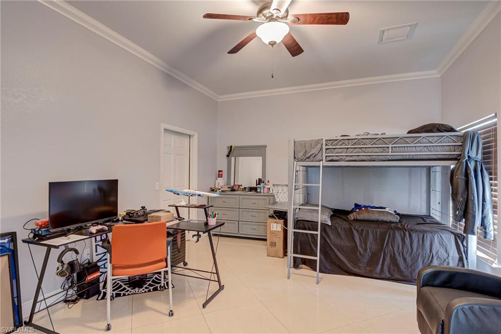 Bedroom featuring a desk, crown molding, a ceiling fan, and light tile patterned floors