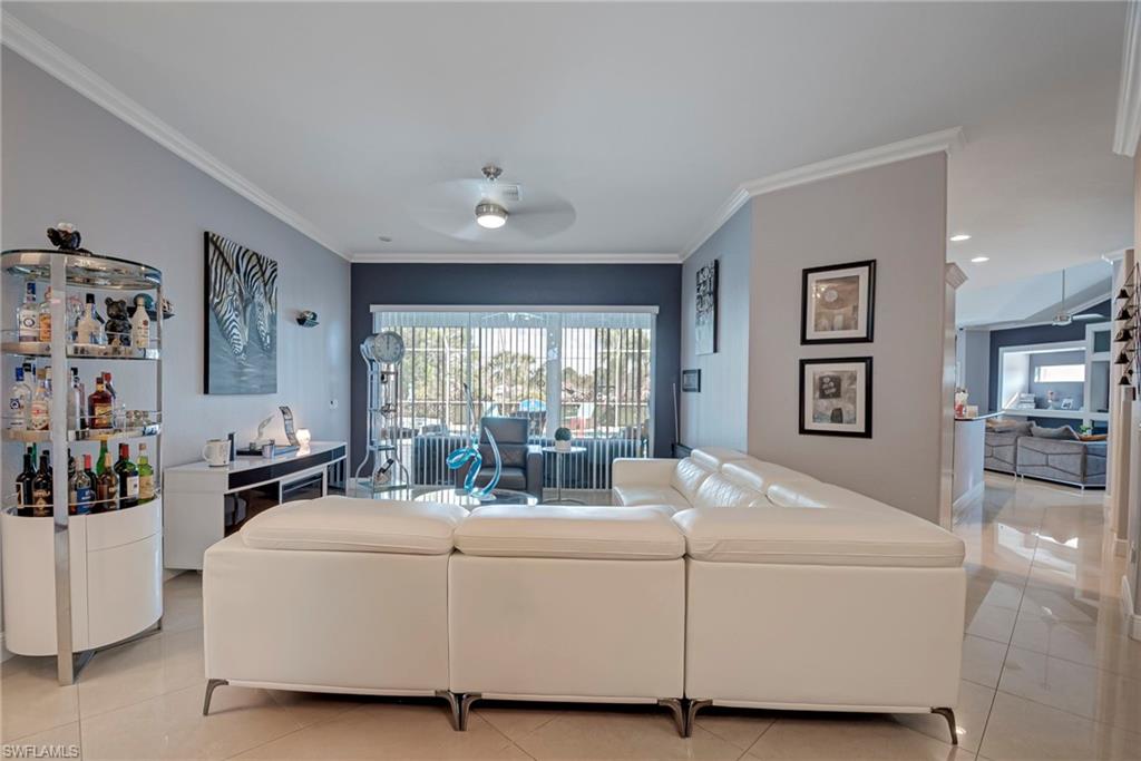 Living area with crown molding, a ceiling fan, and light tile patterned floors
