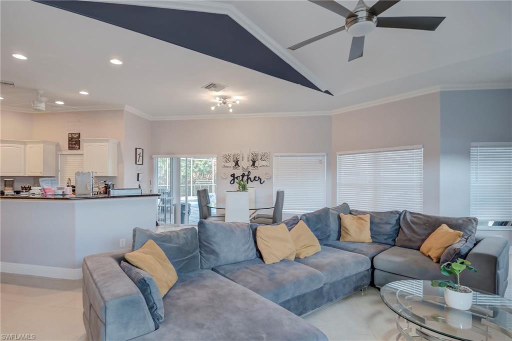 Living area with ceiling fan, crown molding, vaulted ceiling, recessed lighting, and light tile patterned flooring