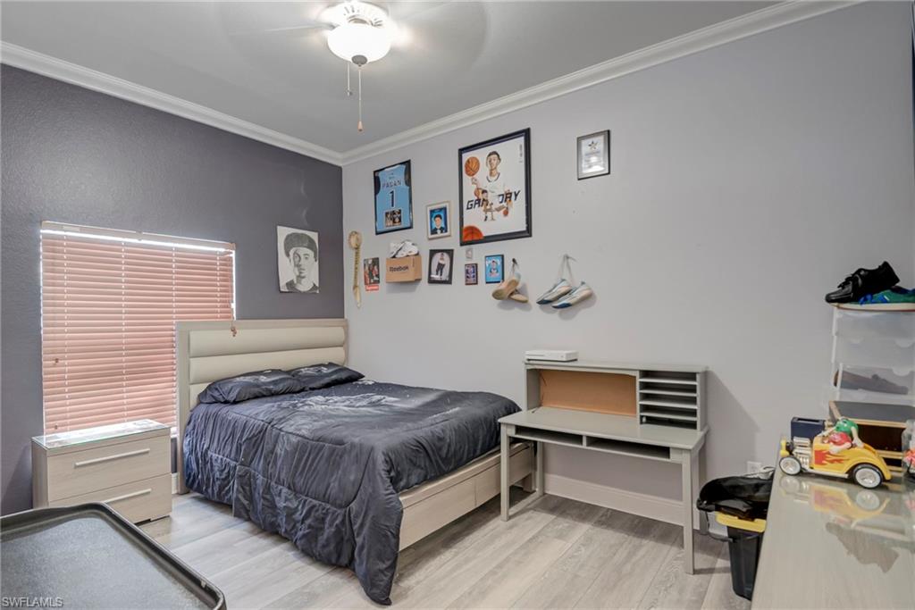Bedroom featuring ornamental molding, light wood-style flooring, and a ceiling fan