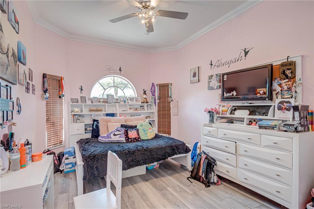 Bedroom with light wood-style floors, crown molding, and ceiling fan