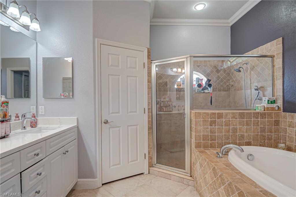 Full bath featuring vanity, crown molding, a bath, and a stall shower