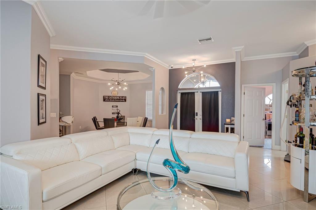 Tiled living area featuring crown molding and suspended lighting