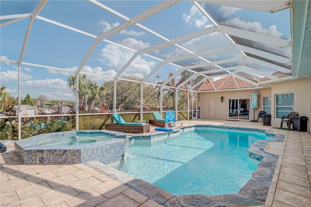 Integrated pool / spa featuring glass enclosure, a sunroom, and a patio area