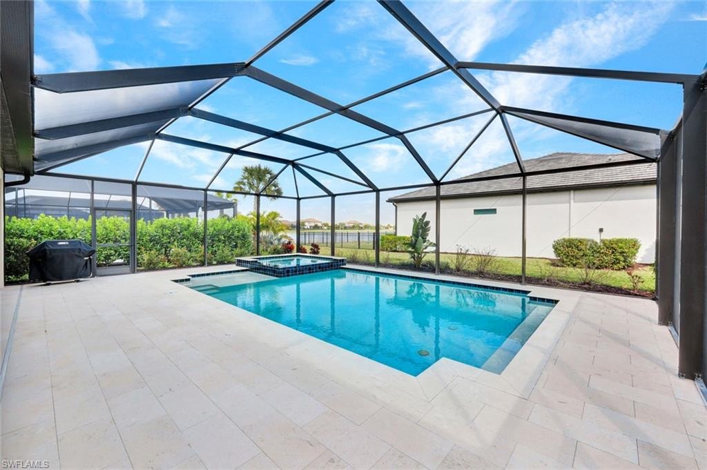 Combined pool / hot tub with a sunroom, a patio area, a lanai, and a grill