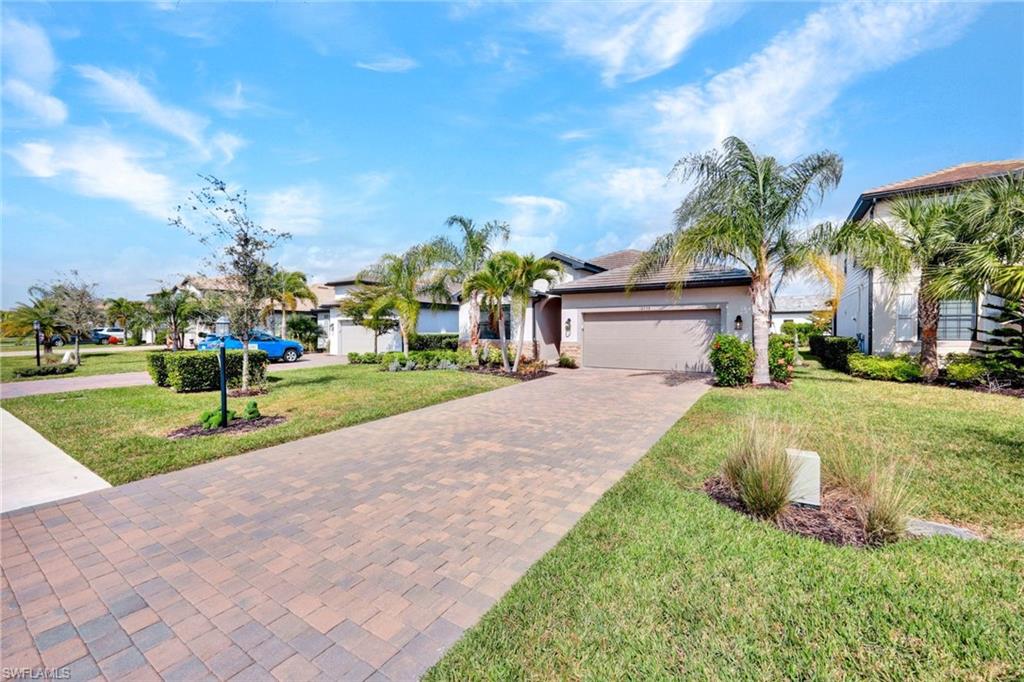 View of front of house featuring decorative driveway, a front lawn, stucco siding, and a garage