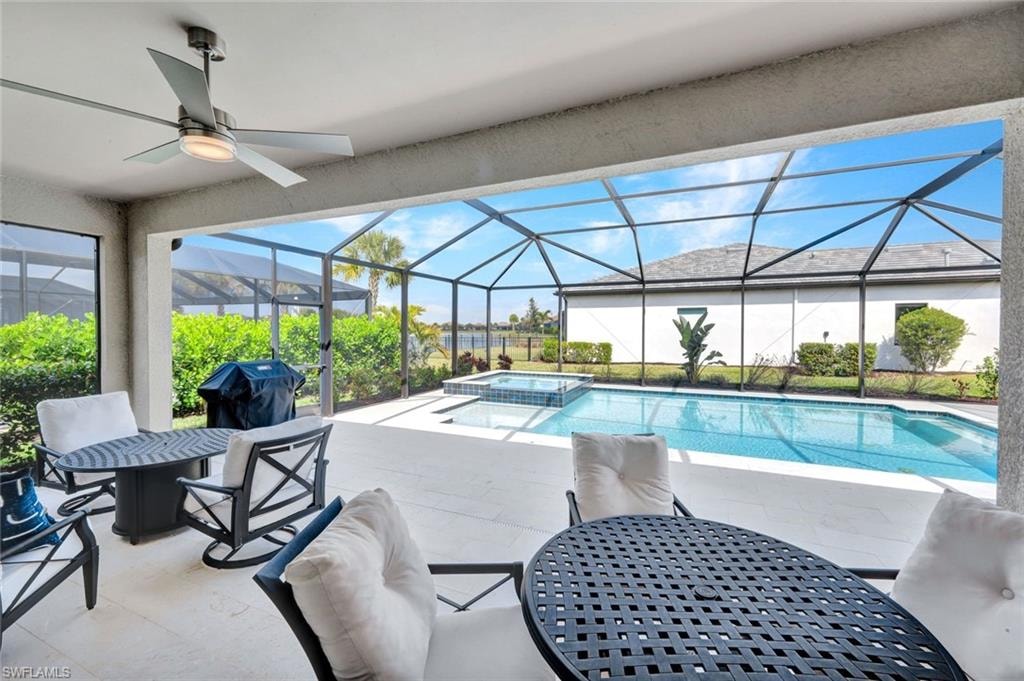 Combined pool / hot tub featuring a patio, a sunroom, a lanai, outdoor dining area, and a grill