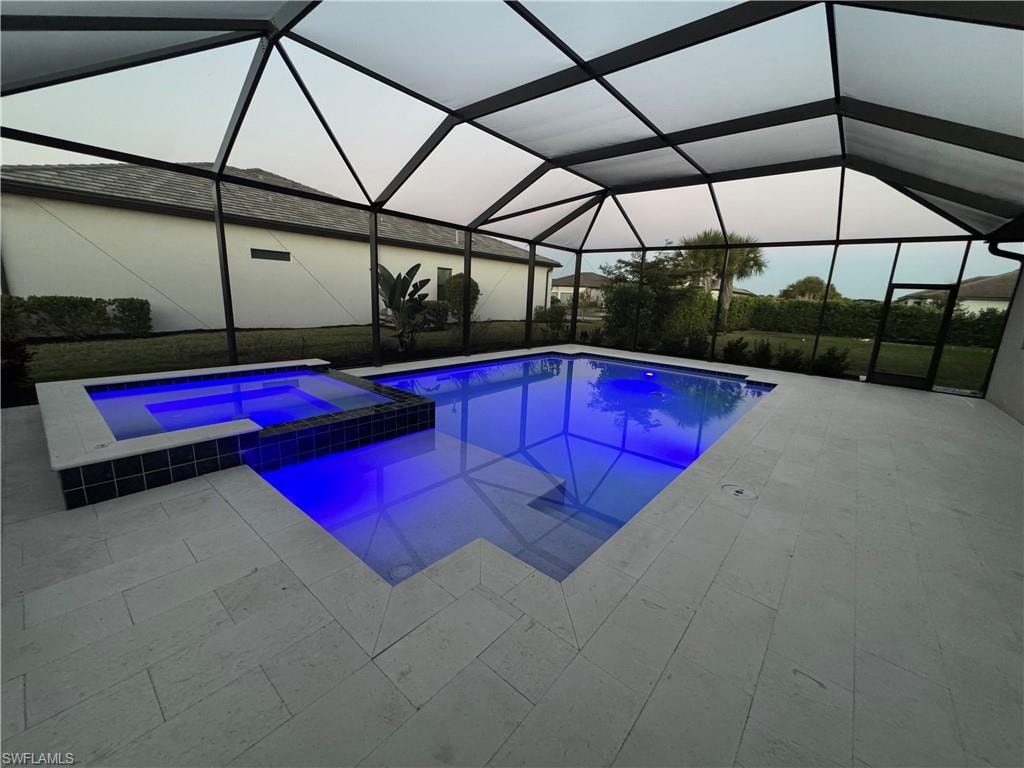 Combined pool / hot tub with a sunroom, a lanai, and a patio area