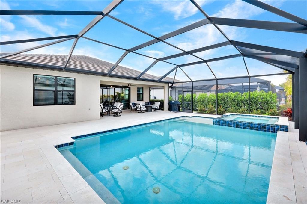 Relaxing pool / spa with a sunroom, glass enclosure, and a patio