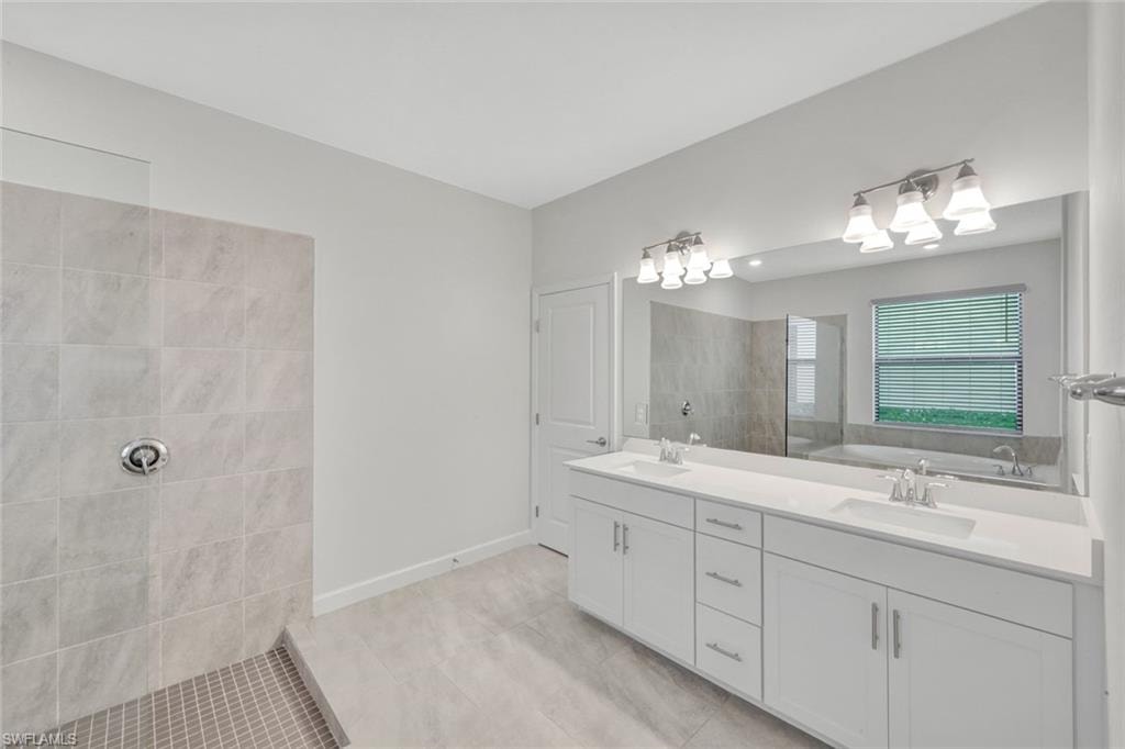 Full bathroom with double vanity, walk in shower, and light tile patterned floors