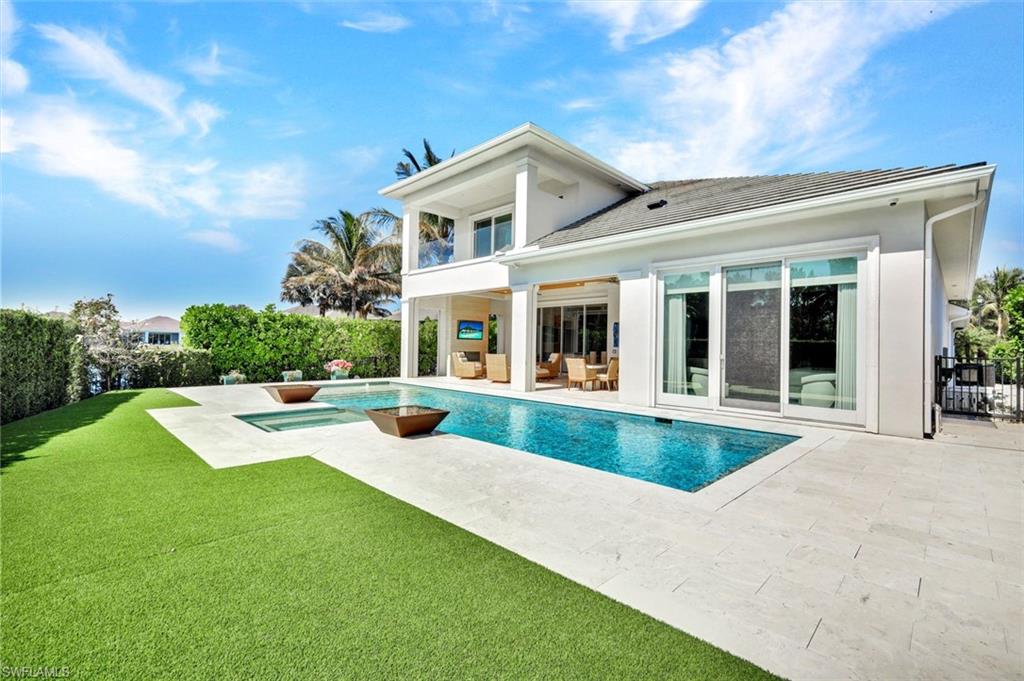 Rear view of house with a balcony, a lawn, and a patio area