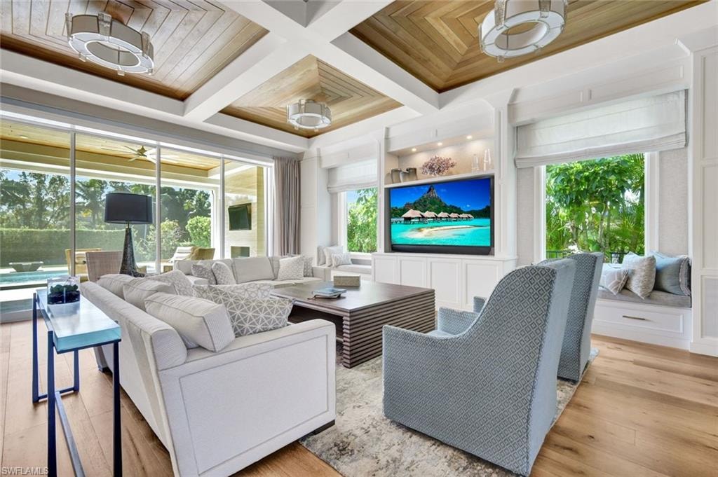 Living room with coffered ceiling, wood finished floors, and a ceiling fan