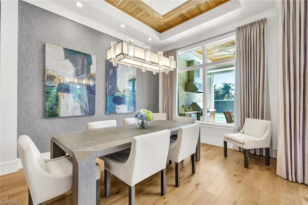 Dining area featuring light wood-style flooring, recessed lighting, and a wood tray ceiling