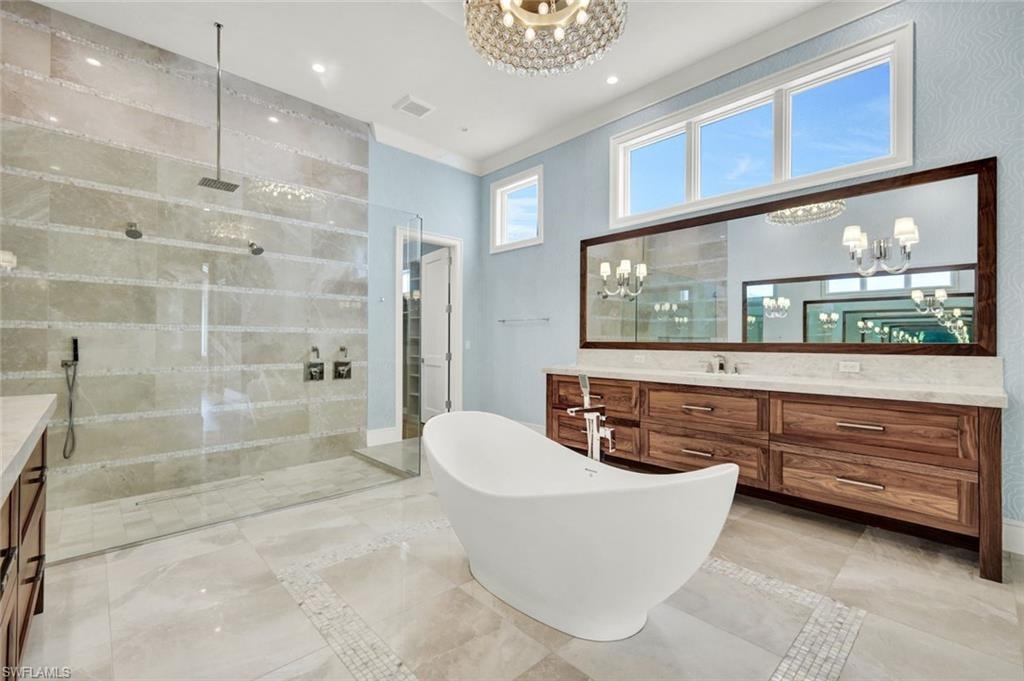 Full bathroom with vanity, a walk in shower, a soaking tub, and hanging lights