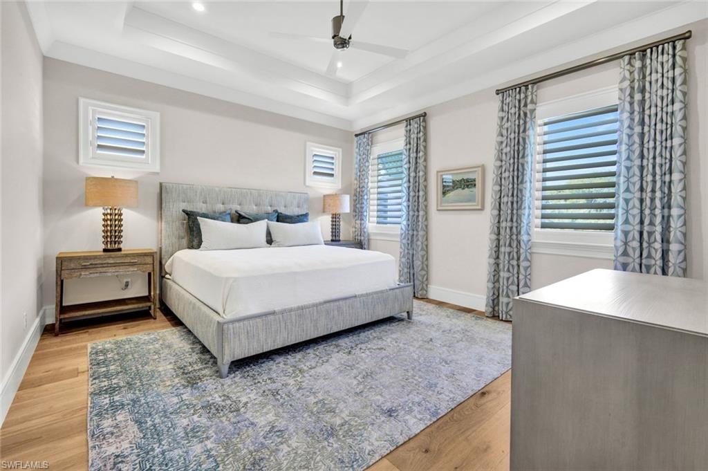 Bedroom with light wood-style floors, a ceiling fan, multiple windows, and recessed lighting
