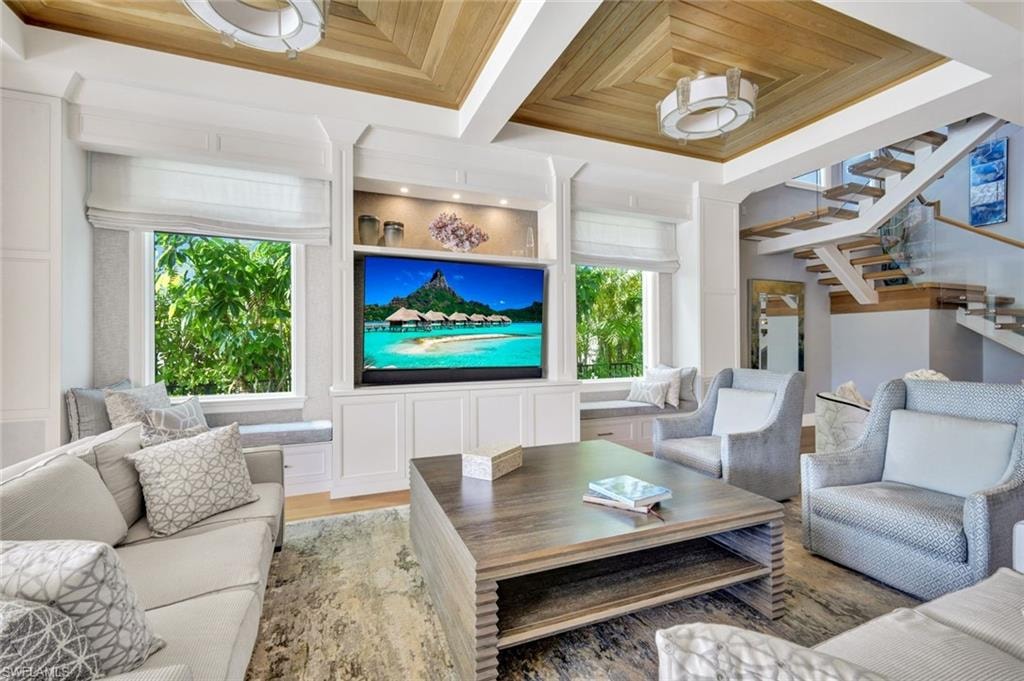 Living room with wood finished floors, ornamental molding, and coffered ceiling
