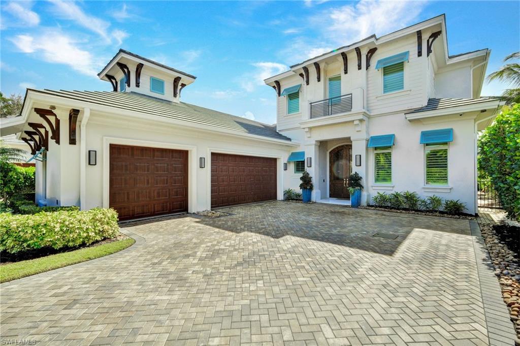 Italianate-style house with decorative driveway, stucco siding, a garage, and a balcony