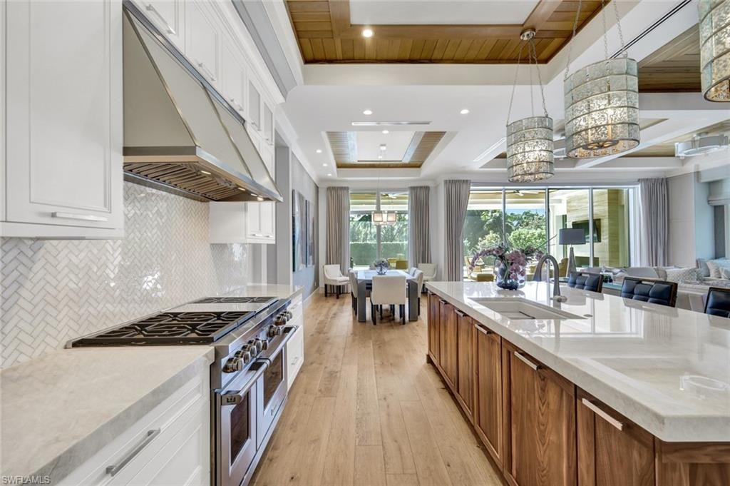 Dual tone kitchen featuring range with two ovens, light stone countertops, dual tone cabinets, open floor plan, and pendant lighting
