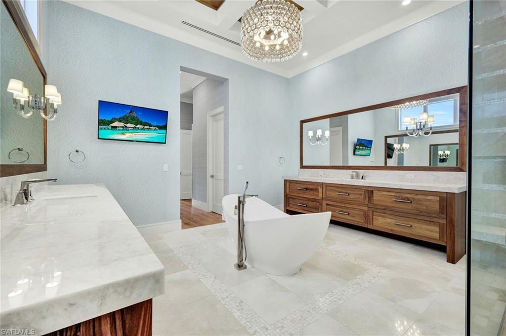 Bathroom with suspended lighting, two vanities, coffered ceiling, a soaking tub, and inlaid floor details
