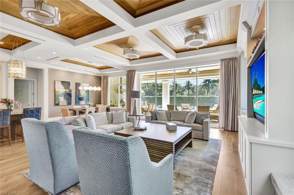 Living room featuring coffered ceiling, light wood-style floors, and suspended lighting