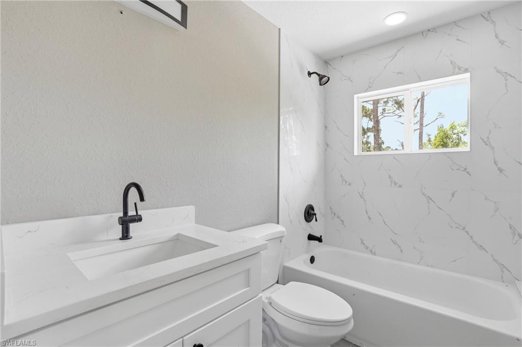 Bathroom featuring a white vanity with an integrated sink, matte black faucet, and a wall-mounted light fixture