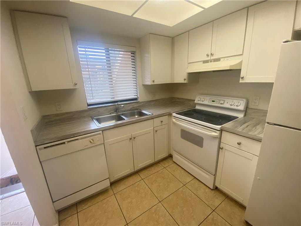 Kitchen featuring white appliances, stainless steel countertops, and white cabinetry