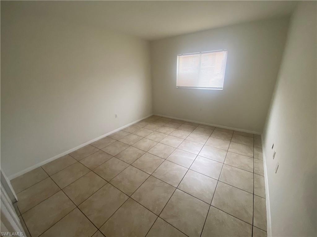 Unfurnished room with light tile patterned floors and baseboards