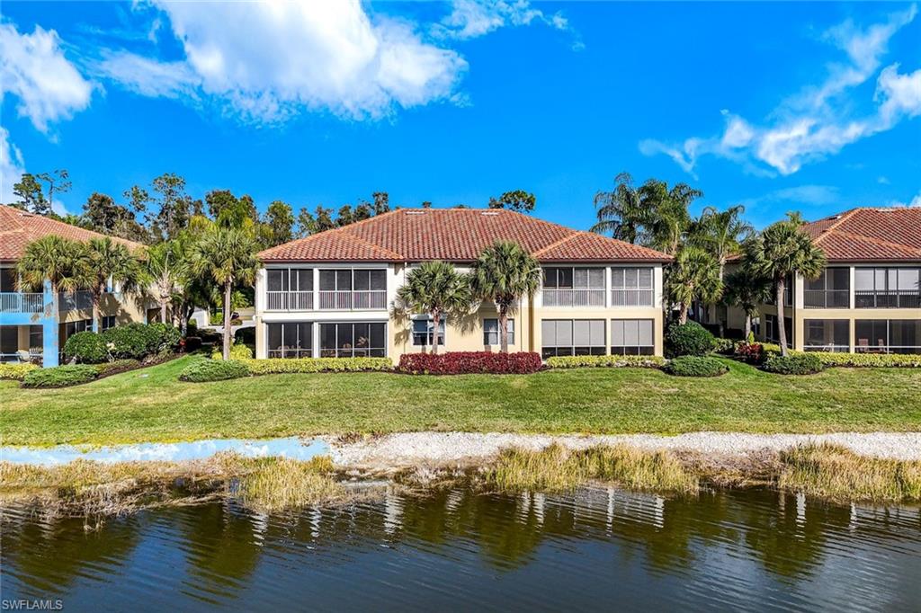 Rear view of property with a tile roof, a water view, stucco siding, and a yard