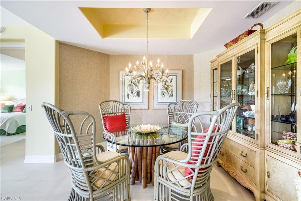 Dining space featuring a raised ceiling, hanging lights, and light tile patterned floors