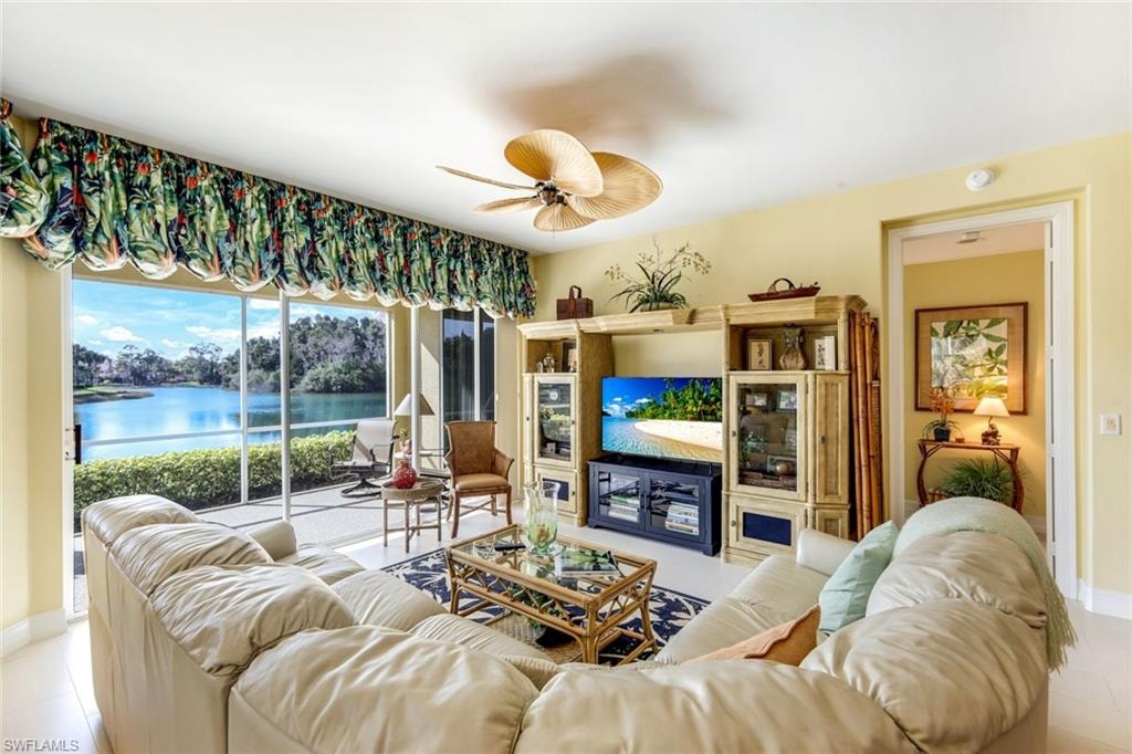 Tiled living room featuring a ceiling fan and a water view