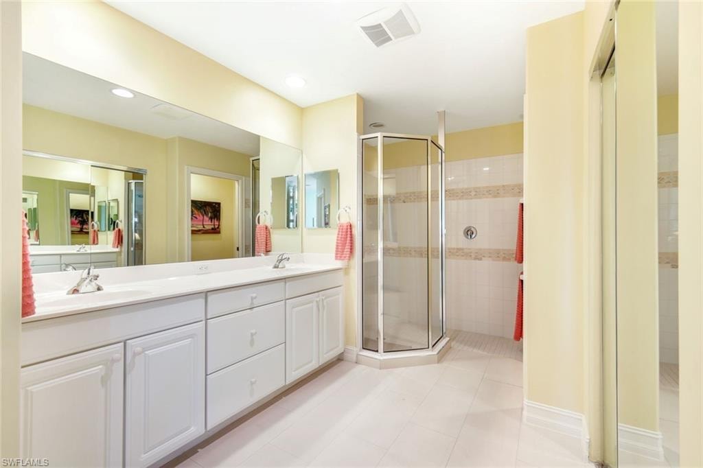 Full bath with double vanity, a stall shower, light tile patterned floors, and recessed lighting