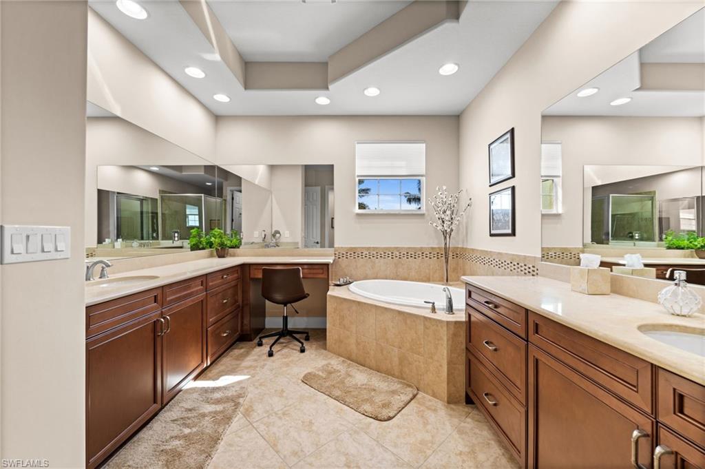 Large primary bath complete with stand up shower, separate tub, his and her sinks and a vanity area