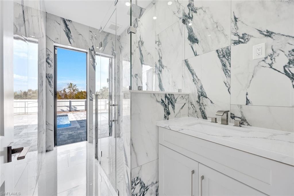 Bathroom with vanity, a marble finish shower, and stone wall
