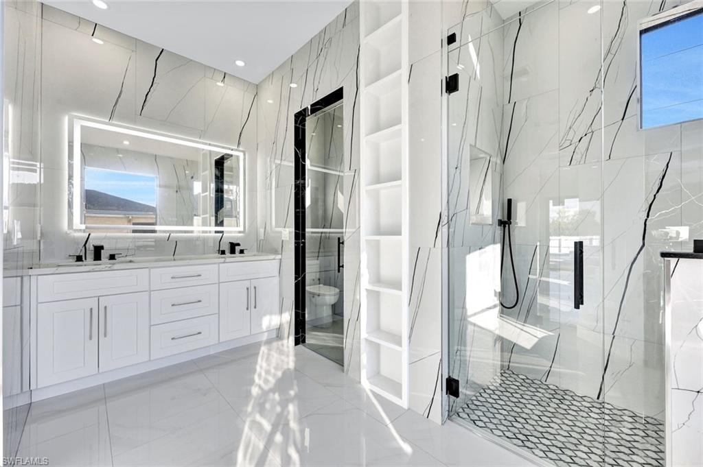 Bathroom featuring double vanity, a marble finish shower, and built in shelves