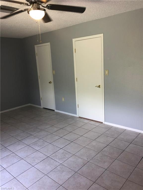 Spare room featuring a textured ceiling, a ceiling fan, and light tile patterned floors