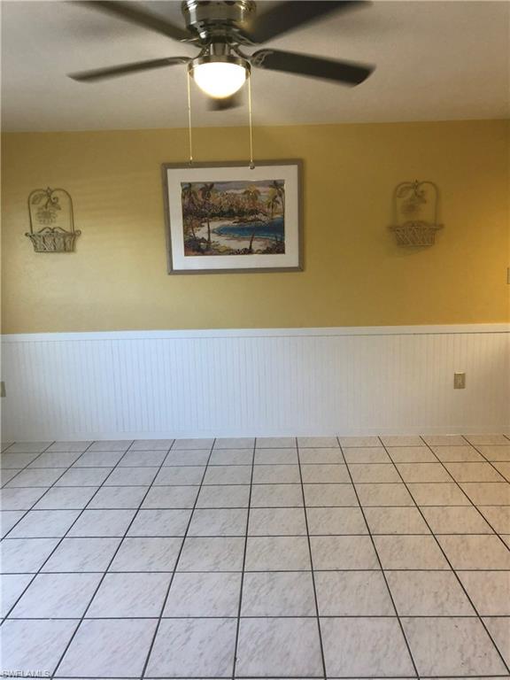 Spare room featuring a wainscoted wall, ceiling fan, and tile patterned flooring