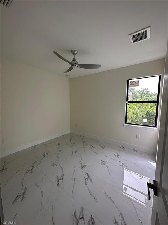 Empty room featuring light marble finish floors and a ceiling fan