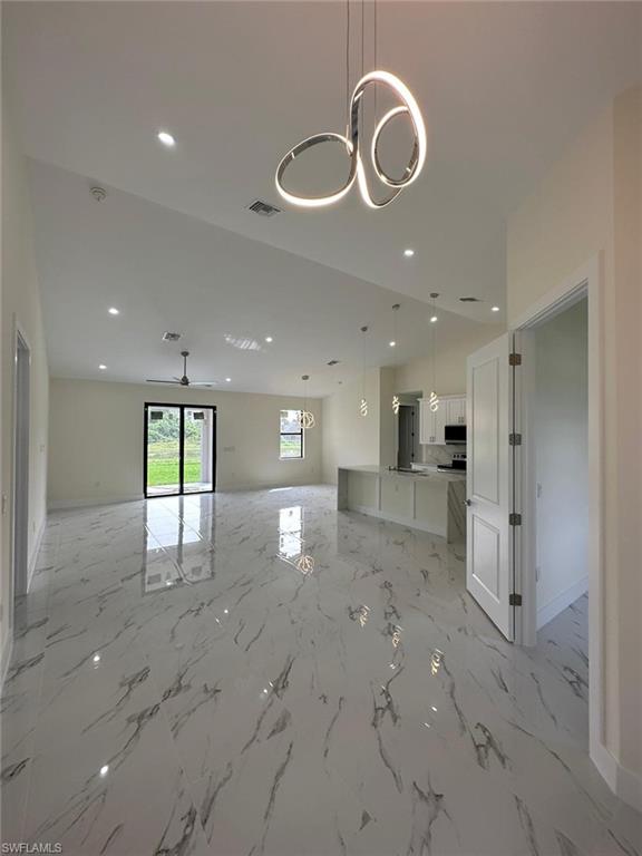 Unfurnished living room featuring hanging lights and light marble finish flooring