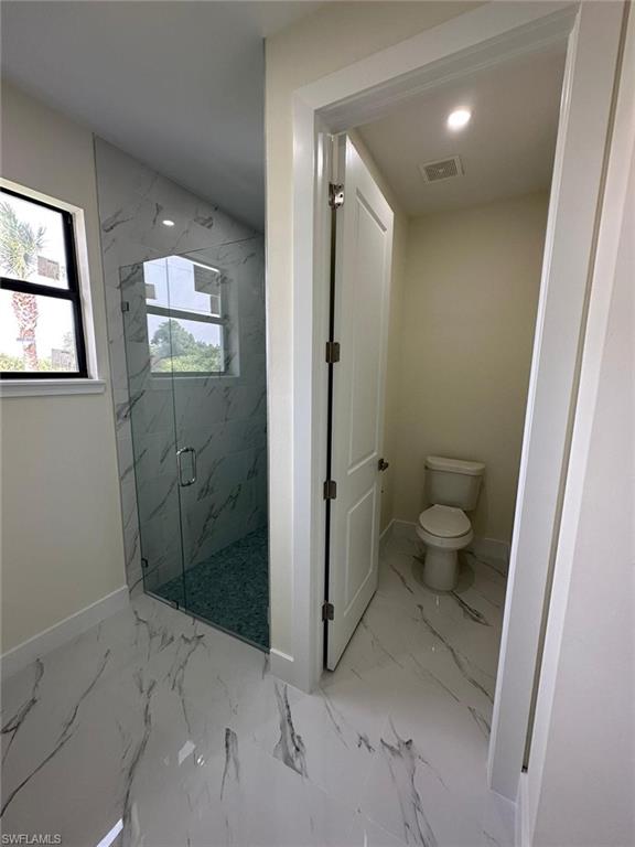 Bathroom with a marble finish shower, light marble finish flooring, and recessed lighting