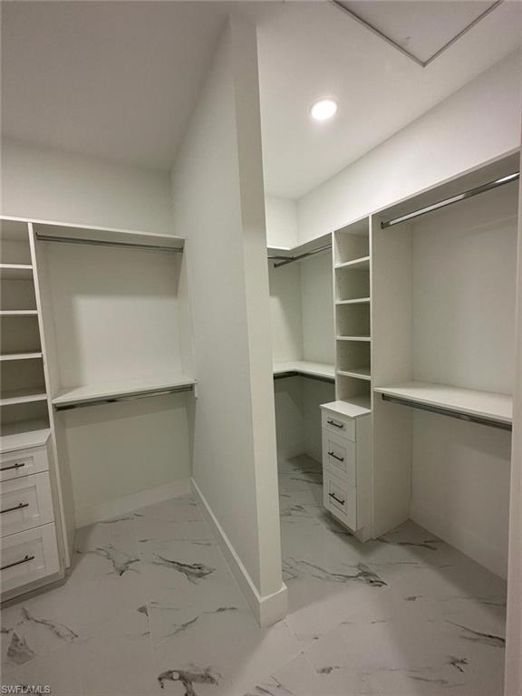 Walk in closet featuring light marble finish flooring