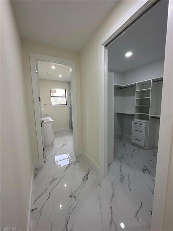 Hallway featuring recessed lighting and light marble finish floors