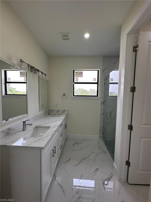 Bathroom with double vanity, a marble finish shower, and recessed lighting