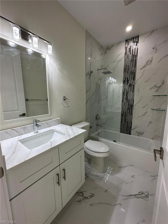 Bathroom with vanity, a combined bath / shower with marble appearance, and light marble finish flooring