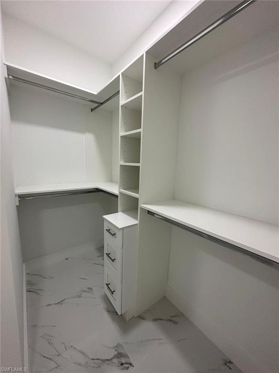 Walk in closet featuring light marble finish floors