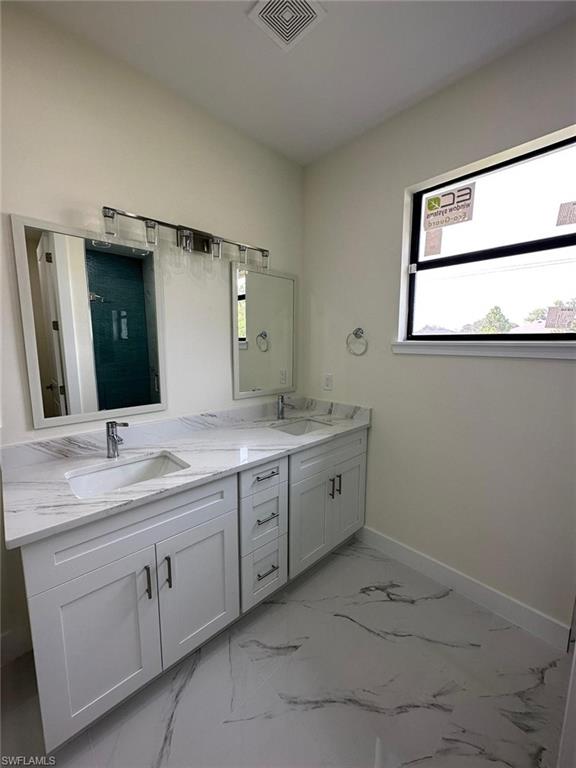 Bathroom with double vanity, a shower, and light marble finish floors