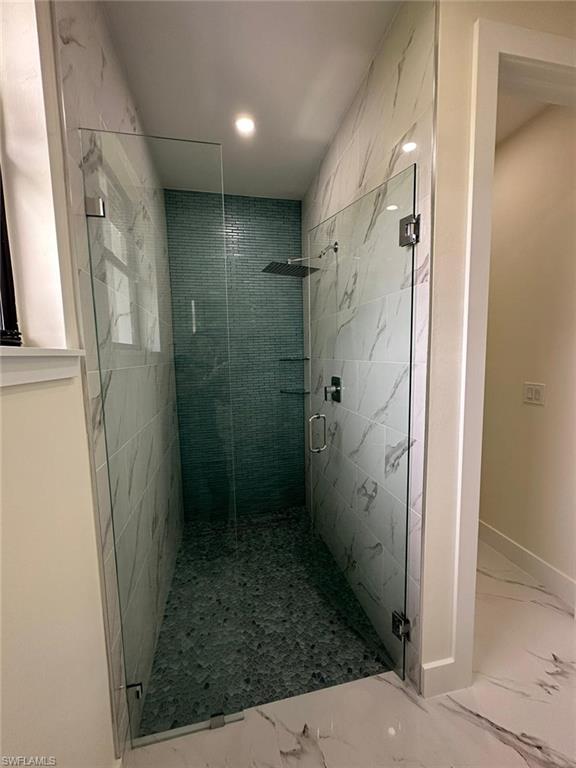 Bathroom featuring marble finish floors, a marble finish shower, and recessed lighting