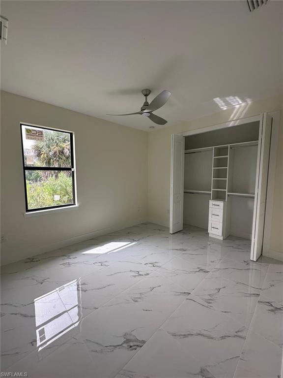 Unfurnished bedroom featuring a closet, ceiling fan, and light marble finish flooring