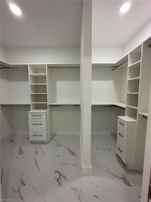 Walk in closet featuring light marble finish flooring