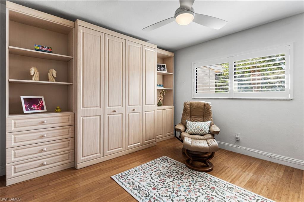 Guest bedroom features wood floors, plantation shutters, and Murphy bed